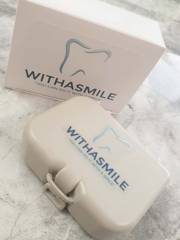 A closed storage box on a table, with the logo for Withasmile dental veneers on the box